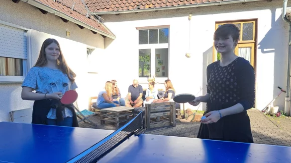 Auch der Au&szlig;enbereich l&auml;dt ein. Zum Beispiel zum Tischtennis, wie hier Nora (14, links) und Kjara (16). Im Hintergrund in der Sitzecke unterhalten sich die Mitarbeiter (von links) Gillian K&ouml;nig, Luzia Hofschr&ouml;er, Holger Busch, Eleni Kousataloglou und Melina von Wysiecki. - &copy; Carolin Brokmann-F&ouml;rster