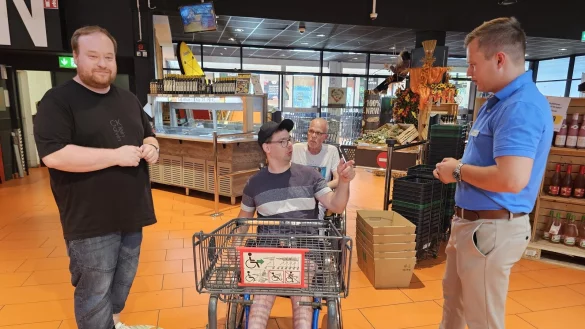 Beim Testeinkauf nutzt Sascha Meier die Gelegenheit, seine Verbesserungsvorschl&auml;ge an Gesch&auml;ftsstellenleiter Luca Konrad (rechts) weiterzugeben. Gut findet er, dass es im Markt sehr viel Platz gibt und er man&ouml;vrieren kann. Mit dem speziellen Einkaufswagen k&auml;me er auch ohne Hilfe seines Betreuers Daniel Jentz (links) zurecht. Der Behindertenbeuaftragte Rolf Tschentscher setzt sich daf&uuml;r ein, dass mehr M&auml;rkte diesen speziellen Wagen anschaffen. - &copy; Astrid Sewing