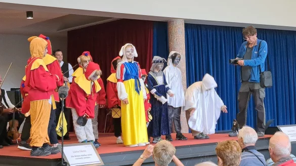 Die kleinen Schauspieler, darunter Zwerge, tanzen auf der B&uuml;hne der Wandelhalle zu Musik des Bad Salzuflen Orchesters. - &copy; Kinderkurzfilmreihe Carlo & Susi