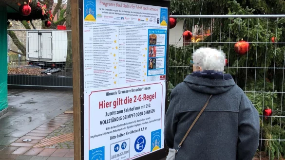 Eine Passantin studiert die Corona-Regeln für das Betreten des Weihnachtstraums auf dem Salzhof. - © Thomas Reineke