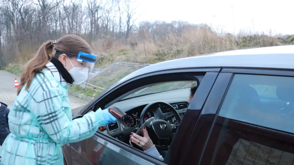 Mirjam Fischer scannt den QR-Code der Autofahrerin, l&auml;sst sich noch den Personalausweis zeigen und holt dann das Test-Kit. - &copy; Birgit Guhlke/Neue Westf&auml;lische