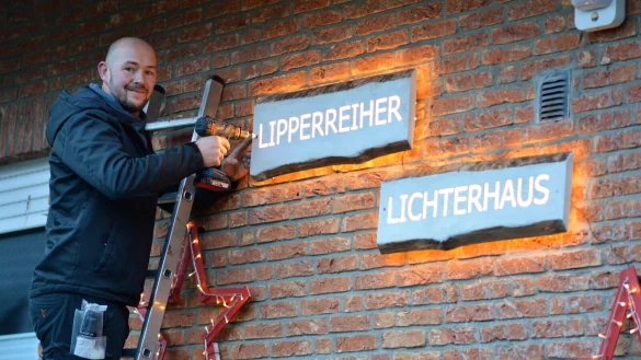 Marco Regenhardt moniert die neuen h&ouml;lzernen Schilder mit den ausgefr&auml;sten Buchstaben an die Hauswand. Mit L&auml;mpchen versehen, leuchten die Worte "Lipperreiher Lichterhaus" auf. - &copy; Karin Prignitz