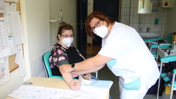 Stephanie Wilk ist mit Freude bei der Arbeit. Auch das Fieber- und Blutdruckmessen gehört zu ihren Aufgaben. Für das Foto hat sich Veronika Rudenski, kommissarische Pflegedienstleiterin, zur Verfügung gestellt. - © Agentur für Arbeit Detmold