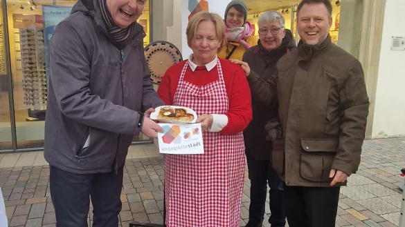 Am Infostand freuten sich Jochen Beuckers (links, Sprecher der Engagierten Stadt NRW) und Hendric Schwär-Fröhlich (rechts, persönlicher Referent des Bürgermeisters) über einen Gruß von Annette Diekmann vom Pickert-Mädel-Stand auf dem Wochenmarkt. - © Stadt Lemgo