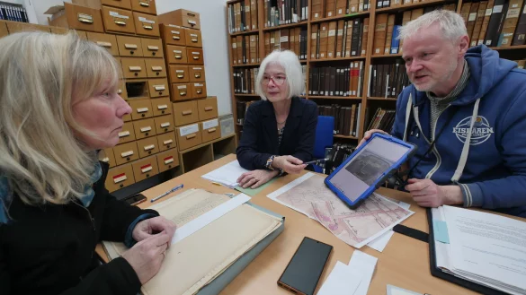 Robert G&uuml;ndchen (Arch&auml;ologe) zeigt Dr. B&auml;rbel Sunderbrink (Stadtarchiv, links) und Dr. Elke Treude (Landesmuseum) ein Foto von der Grabung in der Langen Stra&szlig;e. Mit Hilfe von Dokumenten des Stadtarchiv versuchen alle drei, den Fund einzuordnen. - &copy; Jost Wolf