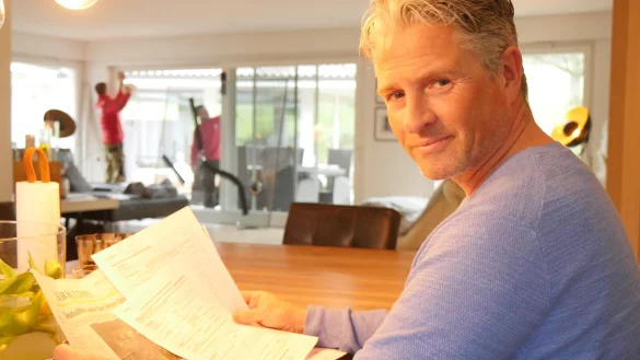 Gunnar Altenfeld mit dem Schadensersatzantrag und dem LZ-Artikel, der ihn auf M&ouml;glichkeit der Man&ouml;verschadensregulierung hinwies. Im Hintergrund tauschen die Fensterbauer Carsten Pape und Sebastian Leszczynski die Scheibe, auf der die Risse notd&uuml;rftig mit Klebeband gesichert sind. - &copy; Jost Wolf