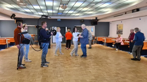Markus Maria Profitlich (im blauen Hemd) &uuml;bt den Tanz zu "Wir sind so viel mehr" mit seiner Frau Ingrid Einfeldt, w&auml;hrend Margret Hey (in der hellblauen Jacke) Anweisungen gibt und Moderatorin Birgit Lechterman (im pinken Blazer) zuschaut. Das Kamerateam h&auml;lt alles in Bild und Ton fest. - &copy; Nadine Uphoff