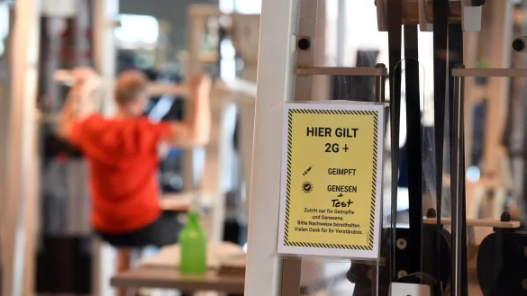 Ein Mann trainiert in einem Fitnessstudio, das bereits im Aushang die 2G+-Regelung hat. - &copy; picture alliance/dpa