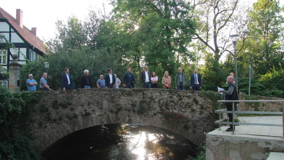 Fred Niemeyer (rechts) zeigt den Vertretern der lokalen Leader-Aktonsgruppe (LAG), was im Ilsepark alles entstanden ist. An der Ilse unterhalb der Br&uuml;cke sind Sitzpl&auml;tze am Wasser entstanden. - &copy; Katrin Kantelberg