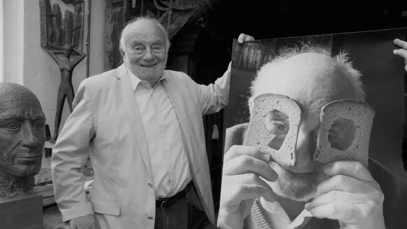 Bruno Buschmann ist f&uuml;r jeden Spa&szlig; zu haben gewesen. Auf dem gro&szlig;formatigen Bild neben ihm blickt der Bildhauer in seinem Oerlinghauser Atelier durch eine 90, die aus zwei Brotscheiben ausgeschnitten worden ist. - &copy; Karin Prignitz