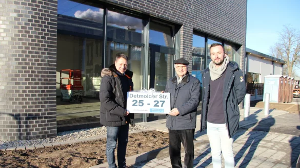 Architekt Nils Duderstadt (links) &uuml;berreicht Investor G&uuml;nther Brandt die Hausnummer des Neubaus. Dieser steht an der Lageschen Stra&szlig;e 25-27. Philipp Schmidt von der zust&auml;ndigen Baufirma hat den Bau begleitet. Im Hintergrund zieht bald Subway ein. Im Geb&auml;udeteil dahinter Jysk. - &copy; Kirsten Fuhrmann