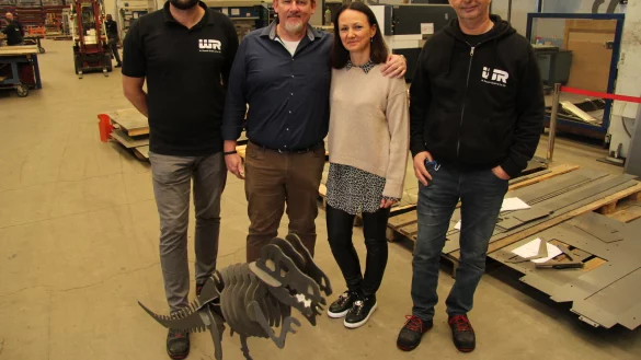 Betriebsleiter Denis Funk (von links), Gesch&auml;ftsf&uuml;hrer Wilbert Rausch, seine Frau Patrizia Rausch und der stellvertretende Betriebsleiter Niko Cerovic stehen mit dem Markenzeichen, einem metallenen T-Rex, in der Produktionshalle. - &copy; Nadine Uphoff