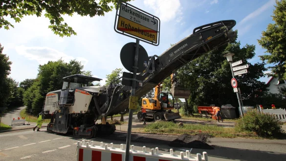 Die Asphaltfr&auml;se frisst sich an der Einm&uuml;ndung der Stra&szlig;e "Im neuen Land" durch den Fahrbahnbelag. Im Hintergrund wartet eine Armada Sattelschlepper, um die Asphaltreste abzutransportieren. - &copy; Jens Rademacher