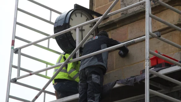 Hubert Ebers (links) und Fritz Röwe montieren die überholte und lackierte Uhr exakt dort, wo sie bis vor 25 Jahren hing. - © Dieter Asbrock
