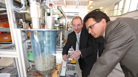 Schauen genau hin: die Initiatoren der Smart-Factory OWL, Dr. Oliver Herrmann (links) und Prof. Jürgen Jasperneite, an der Popcorn-Maschine, die selbst Maisnachschub organisieren soll. - © Vera Gerstendorf-Welle