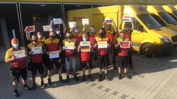 Menschen unterschiedlicher Nationalitäten arbeiten bei DHL in Lemgo. 
Die Postler haben eine deutliche Botschaft. - © Deutsche Post DHL Group