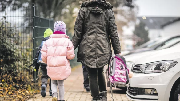 &Uuml;berbeh&uuml;tend: Eine Mutter tr&auml;gt ihrer Tochter den Schulranzen zum Unterricht. - &copy; dpa