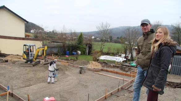 Svantje und Lars Heidemann stehen am Rand der Baugrube, wo zwei Arbeiter gerade den Untergrund f&uuml;r das Betonfundament ihres neuen Hauses vorbereiten. Bis Ende der Woche soll es gegossen sein. - &copy; Dieter Asbrock