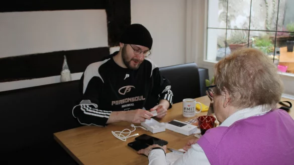 Winston Linford von der Volkshochschule erklärt einer Seniorin das Übertragen von Daten auf ihr neues Handy. - © Raffael Giebel