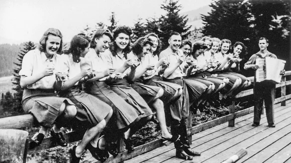 Fr&ouml;hliches Lachen in die Kamera: Junge SS-Helferinnen und Karl-Friedrich H&ouml;cker (Mitte) l&ouml;ffeln auf der Terrasse des SS-Ferienheimes in der N&auml;he von Auschwitz genie&szlig;erisch Blaubeeren aus einem Sch&auml;lchen. - &copy; United States Holocaust Memorial Museum