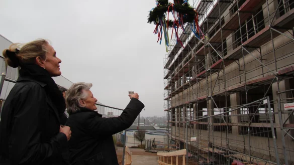 Den Richtkranz im Blick: Gesellschafterin Klara Niehus (geborene Brasseler) hebt ein Glas vor dem Neubau. Links im Bild steht ihre Tochter  Anke Niehus. - &copy; Thomas Reineke
