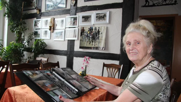 Einst und jetzt: Ingried Steinnagel bl&auml;ttert in dem Fotoalbum, das das Hof-Caf&eacute; im abbruchreifen Rohzustand zeigt. Mit dem schmucken Fachwerkhaus von heute hat es wenig gemein. Die Wand zieren Fotos aus dem Trabrennsport, dem das Trabergest&uuml;t Diekhof &uuml;ber Jahrzehnte verbunden war. - &copy; Dieter Asbrock