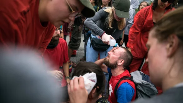 Chaos: Das Foto zeigt, wie andere Teilnehmer der Demonstration Manuel Wiemann Augen und Gesicht mit Wasser auswaschen. Er wurde von Reizgas getroffen. - &copy; Gordon Welters