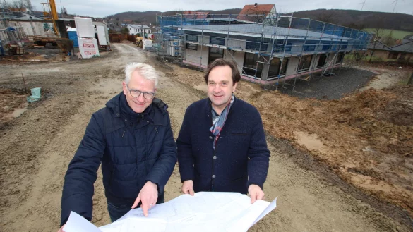 Jobst-Bernd H&ouml;fer (links) und Nils Ackermann blicken in die Pl&auml;ne, w&auml;hrend im Hintergrund der Wohnpark Kalletal entsteht. - &copy; Jens Rademacher
