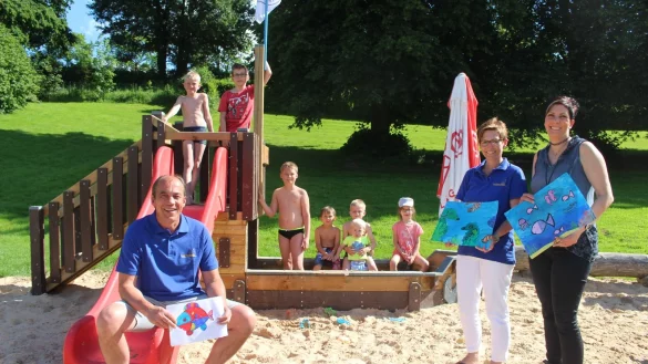 Piraten ahoi: (vorn, von links) Betreiber Rolf Stanislawski , Dagmar Schultz, Vorsitzende des F&ouml;rdervereins, und die K&uuml;nstlerin Marion Doxie Delaubell pr&auml;sentieren die Fische, die die Sch&uuml;ler f&uuml;r die noch triste Mauer im Freibad gemalt haben. Die Kinder (hinten, von links) Jano (10), Leon (12), Lucas (10), Ruben (5), Jerome (9), Fynn (1) und Emilia (6) haben auf dem neuen Piratenschiff, das von der SPD gesponsert wurde, sehr viel Spa&szlig;. - &copy; Michaela Wei&szlig;e