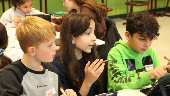 Die Achtkl&auml;sslerin Fay (Mitte) erkl&auml;rt den Grundsch&uuml;lern Jouni (rechts) und Mats (links) die Feinheiten der 3D-Druck-Design App auf dem Tablet. - &copy; Philipp Kersten