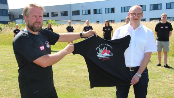 Schulsozialarbeiter Paul Oehlschl&auml;ger (links) organisiert die Lauf-AG und h&auml;lt mit KEB-Ausbildungsleiter Thomas Lalk die T-Shirtsspende. &Uuml;ber die Shirts freuen sich (von rechts) Patrick, Jesko, Tim, Lucy, Nele, Sarah, Pia, Lea, Annika. - &copy; Seda Hagemann