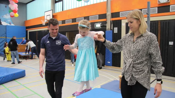 Die vierj&auml;hrige Emilia balanciert als Prinzessin Elsa verkleidet auf der Slackline. Mama Piera Meier und Jannik Schalofsky vom TBV Jahn Alverdissen reichen ihr die Hand. - &copy; Nadine Uphoff