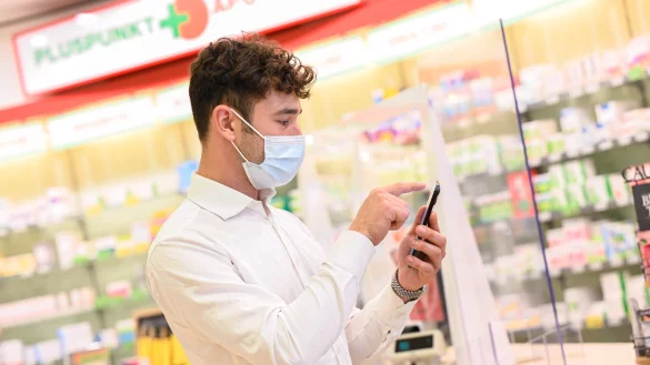 Ein Mann h&auml;lt in einer Apotheke sein Handy in der Hand. Ist jetzt Schluss mit der Zettelwirtschaft? - &copy; Mohssen Assanimoghaddam/dpa
