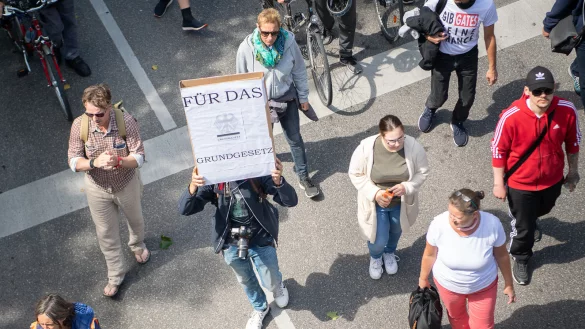 Ein Mann hält während einer Demonstration der Initiative «Querdenken 711» gegen die Corona-Maßnahmen ein Schild, auf dem «Für das Grundgesetz» steht, hoch. - © Symbolbild: Sebastian Gollnow/dpa
