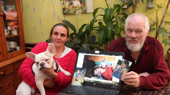 Margitta und Thomas M&uuml;ller und Therapieh&uuml;ndin Angel mit Fotos von Julian. Das mittlere Bild zeigt ihn kurz vor seinem Tod mit den Therapiehunden Rio und Angel. Links daneben ein Foto des dreij&auml;hrigen Julian mit Rebecca und rechts ein Bild, da ist er sechs Jahre alt. - &copy; Bernhard Preuss