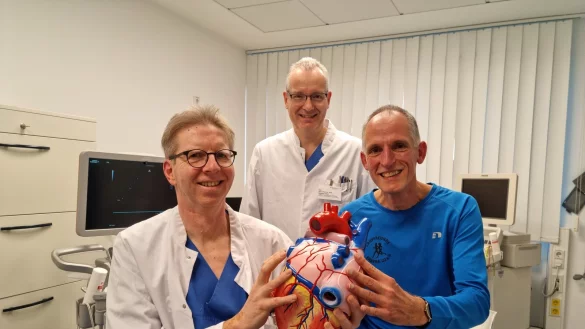 Oberarzt Dr. Johannes Brockmeier (von links) und Chefarzt Dr. Stefan Gielen sind froh, dass es Friedrich-Wilhelm Althof heute wieder gut geht. Am Herzmodell zeigen Brockmeier und Althof die Lungenvenen in blau, die bei Althof verödet wurden, um sein Vorhofflimmern zu behandeln. - © Carolin Brokmann-Förster