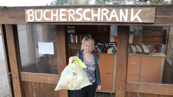 Ehemaliges Bush&auml;uschen: Sabine Beine r&auml;umt wieder einmal den offenen B&uuml;cherschrank in Belle auf und h&auml;lt einen gelben Sack in der Hand, der dort illegal entsorgt wurde. - &copy; Guntmar Wolff