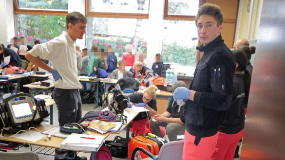 Provisorischer Behandlungsraum: Drei Ärzte schauen nach, ob die Kinder Rötungen im Rachenraum haben und fragen sie nach einem Hustenreiz. Alle Befunde werden akribisch notiert. - © Corina Lass