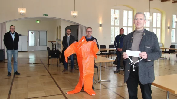 B&uuml;rgermeister Stefan Rother (vorne) zeigt einen einfachen Mundschutz der Firma Vorndamme (Isotemp), Heinz Blome (Ordnungsamt) einen orangen Schutzoverall. Im Hintergrund (von links) Rainer Holste (Ordnungsamt), Tim S&ouml;lter (Zentrale Dienste) und Stephan Beinker (Baubetriebshof/Feuerwehr). - &copy; Dieter Asbrock
