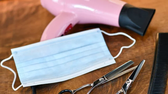 Friseurscheren und Kamm liegen neben Maske und Haartrockner. - &copy; Foto: Kirsten Neumann/dpa-tmn