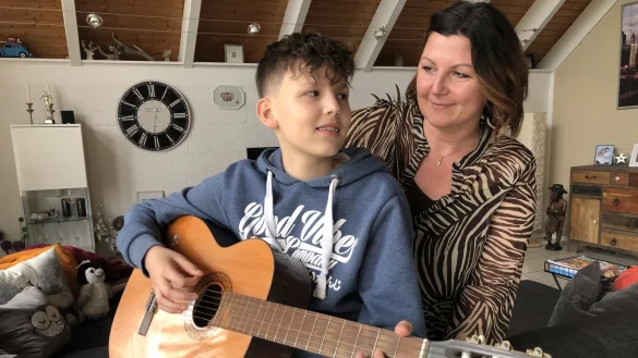 Luc und Sandra Kiefer sitzen auf der Couch im Wohnzimmer. Seit gut vier Jahren spielt der 13-J&auml;hrige Gitarre. - &copy; Sven Kienscherf