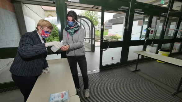 Grabbe-Schulleiterin Daniela Faude und Lehrerin Nadine Schlottmann f&uuml;hren vor, wie sich die Sch&uuml;ler vor den Abiturpr&uuml;fungen am Geb&auml;udeeingang die H&auml;nde desinfizieren k&ouml;nnen. Die Gittert&uuml;ren des &bdquo;L&ouml;wengangs" zum Altbau im Hintergrund werden geschlossen bleiben. Am Eingang und in den Treppenh&auml;usern gilt eine Einbahnstra&szlig;enregelung. - &copy; Jost Wolf