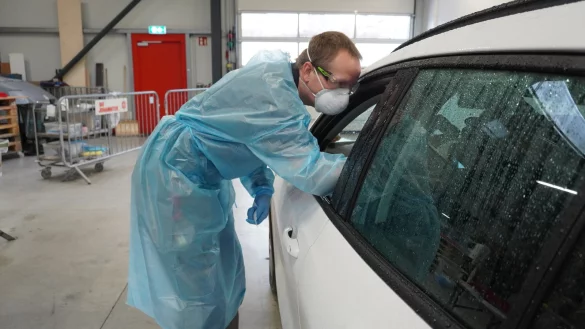 Jens Hollmann, examinierte Fachkraft der Johanniter-Unfall-Hilfe, f&uuml;hrt durch das ge&ouml;ffnete Autofenster den Schnelltest durch. Daf&uuml;r f&auml;hrt er mit einem St&auml;bchen in die Nase der Testperson, um einen Abstrich zu entnehmen. - &copy; Michaela Wei&szlig;e