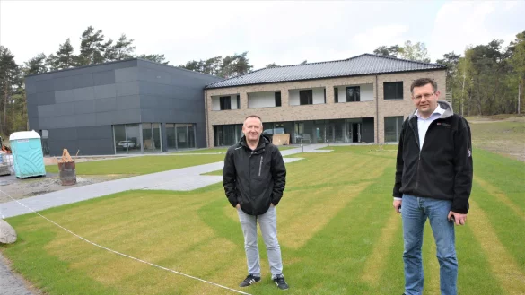 Heimleiter Friedrich Erlenbusch (l.) und Gemeindepastor David Wiebe stehen auf dem Rollrasen vor dem neuen, schucken Geb&auml;ude der "Windrose" am Stukenbrocker Weg. Links ist die Turnhalle zu sehen. - &copy; Karin Prignitz