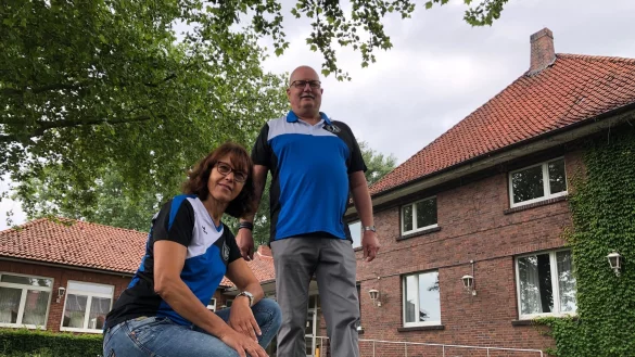 Silke Rehmeier und Detlev Siewert vom Vorstand der Turngemeinschaft Sch&ouml;tmar stehen auf dem Rasen vor der Festhalle. Rechts ist das 90 Jahre alte Gem&auml;uer zu sehen, links hinten der Anbau, der sp&auml;ter dazu kam und in dem sich der kleine Saal befindet. - &copy; Sven Kienscherf