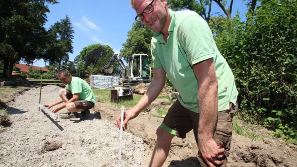 Weg wird barrierearm: Firmenchef Michael Winter (vorn) und Ralf Weber haben im &bdquo;Park im Potenzial" die Treppenstufen zur Waldstra&szlig;e hin entfernt und legen einen Weg an. Die Pflastersteine lagern schon im Hintergrund. - &copy; Jens Rademacher