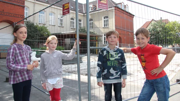 Baustelle auf dem Schulhof: Die OGS-Ferienspielkinder Carlotta, Anna, Mylo und Bent (von links) vor dem Bauzaun. - © Cordula Gröne