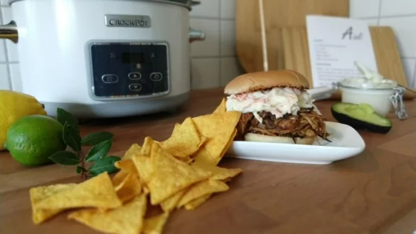 Üppig beladen: Nach 20 Stunden kommt das Fleisch für "Pulled Pork" aus dem Slow-Cooker, wird zerrupft und auf einem Burgerbrötchen angerichtet. Dazu passen Krautsalat, Nacho-Chips und ein Dip. - © Yvonne Glandien