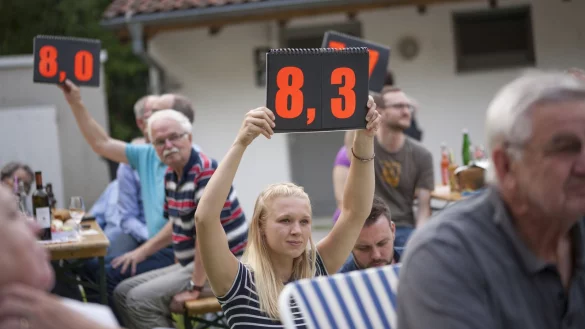 Die Zuschauer entscheiden: Fünf Juroren aus dem Publikum vergeben beim Dichterwettstreit im Freilichtmuseum die Punkte, die sie auf Tafeln in die Höhe halten. - © Laurenz Tegethoff