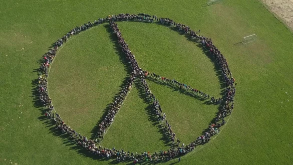 1300 Sch&uuml;lerinnen und Sch&uuml;ler der Karla-Raveh-Gesamtschule haben sich zu einem gro&szlig;en Peace-Zeichen aufgestellt und mit einer Drohne aufgenommen. - &copy; Karla-Raveh-Gesamtschule